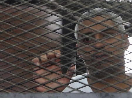 Al Jazeera journalist Mohammed Fahmy stands behind bars at a court in Cairo