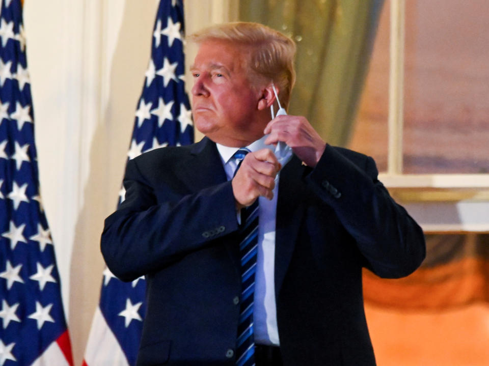 Donald Trump pulls off his protective face mask at the White House after returning from Covid treatment at Walter Reed Medical Center on 5 October, 2020REUTERS