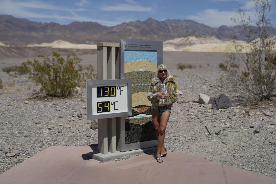 FILE - A woman poses by a thermometer, Sunday, July 16, 2023, in Death Valley National Park, Calif. In the past 30 days, nearly 5,000 heat and rainfall records have been broken or tied in the United States and more than 10,000 records set globally, according to the National Oceanic and Atmospheric Administration. Since 2000, the U.S. is setting about twice as many heat records as cold. (AP Photo/John Locher, File)