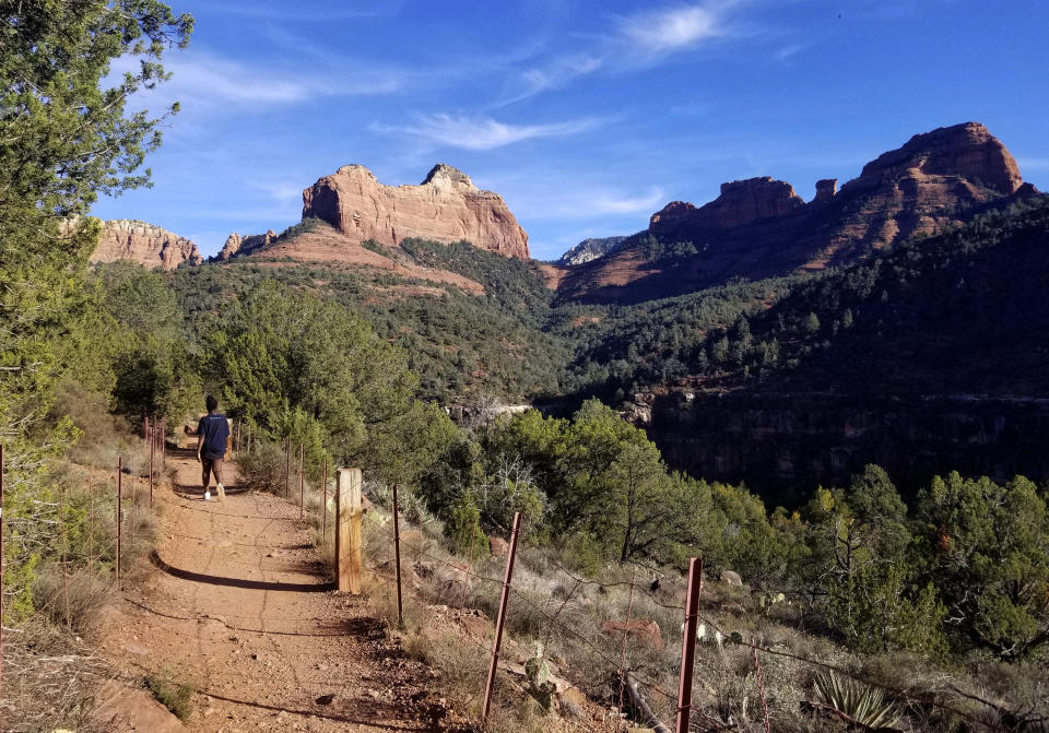 In this 2018 photo a visitor hikes the Huckaby Trail on the way to Oak Creek in the Coconino National Forest in Sedona, Ariz. The sleepy Arizona town of Sedona has long been a refuge for hikers, romantics and soul searchers. There’s picturesque beauty in its earth-toned buildings and also in the glowing red rocks that surround town. And many visitors come looking for something besides this beauty: the so-called vortex where some say the earth’s energy crackles and creates sensations of healing and spiritual awakening. (AP Photo/Joseph Gedeon)