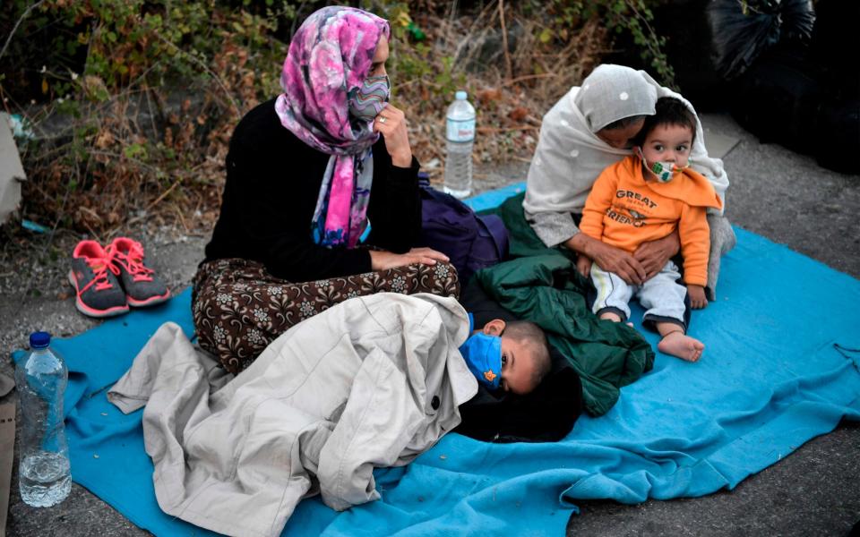 A refugee family sitting in the road after Moria camp was destroyed by fire - AFP