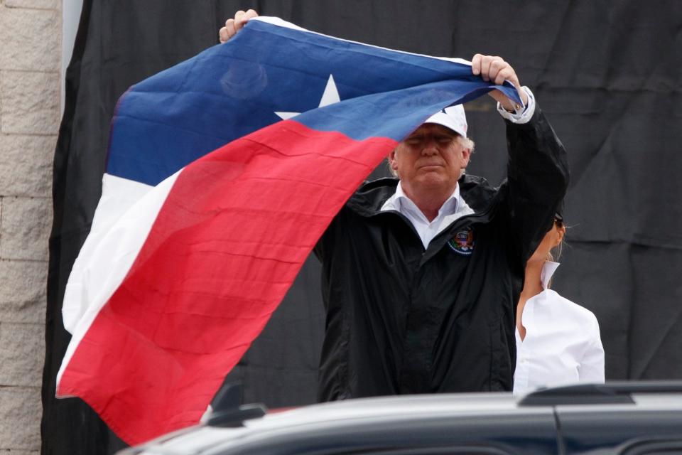 President Donald Trump hoists the Texas flag after speaking with supporters outside Firehouse 5  in Corpus Christi on Tuesday, Aug. 29. Trump received a briefing on Harvey relief efforts while in the city.