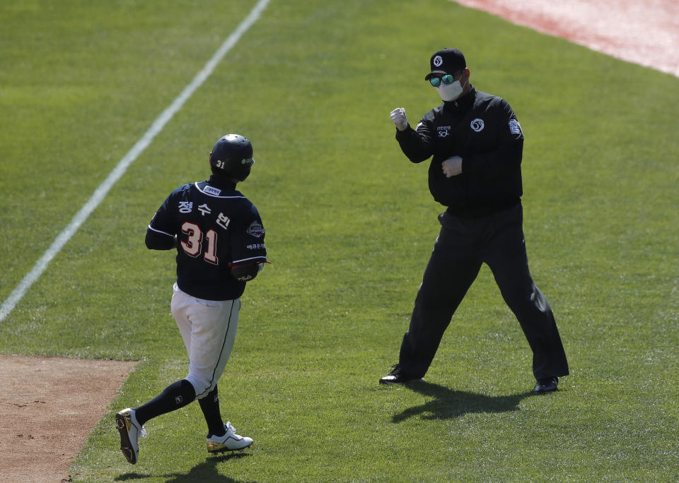 First base umpire Lee Gye-sung, right, wearing a mask and gloves as a precaution against the new coronavirus calls Doosan Bears' Jung Soo-bin out during the pre-season baseball game between Doosan Bears and LG Twins in Seoul, South Korea, Tuesday, April 21, 2020. South Korea's professional baseball league has decided to begin its new season on May 5, initially without fans, following a postponement over the coronavirus. (AP Photo/Lee Jin-man)