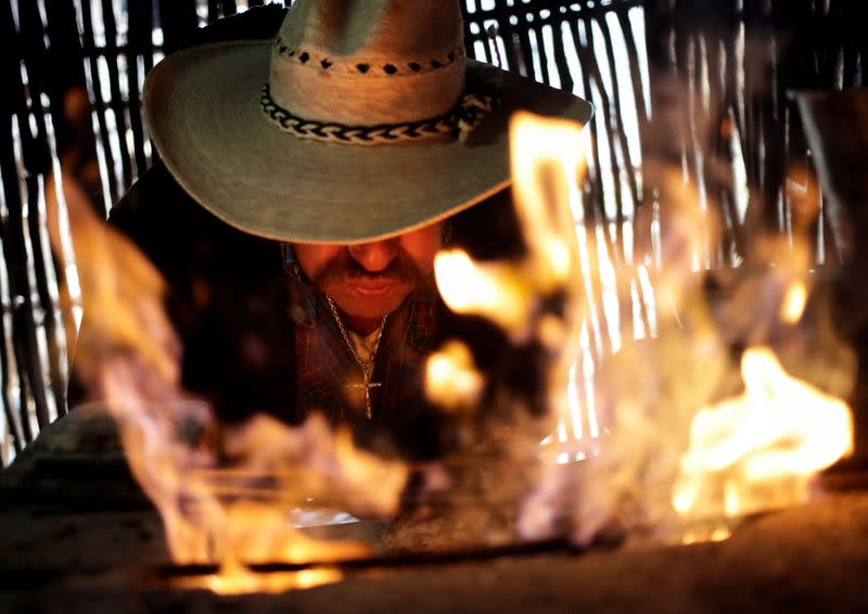 Paulo Ramirez blows air on a fire at his farm in Jalpan de Serra