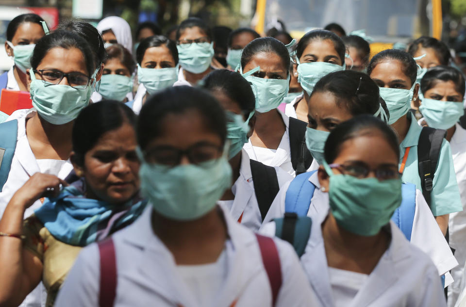 FILE - In this March 6, 2020, file photo, Indian nursing students wearing masks walk in a group at government run Gandhi Hospital in Hyderabad, India. As cases of the coronavirus surge in Italy, Iran, South Korea, the U.S. and elsewhere, many scientists say it's plain that the world is in the grips of a pandemic — a serious global outbreak. (AP Photo/Mahesh Kumar A.)