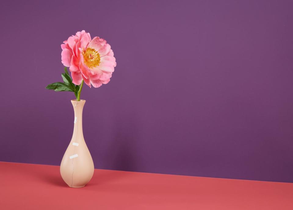 pink flower in ceramic vase being held together with bandages