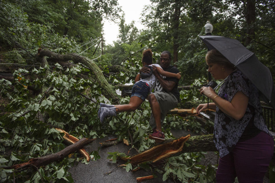 Dwight Ford hands over his daughter Jasmine, 8, to her mother, Laura Stallings, after the car they were driving in was struck by a falling pole that had itself been hit by a lightning bolt after a suspected tornado tore through Charleston, W.Va., Monday, June 24, 2019. (Craig Hudson/Charleston Gazette-Mail via AP)