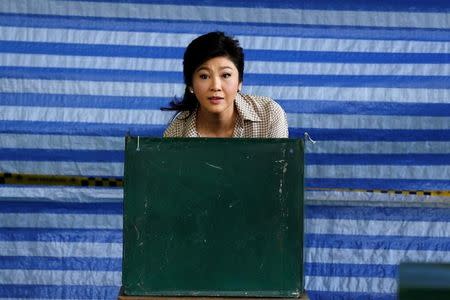 Former Thai Prime Minister Yingluck Shinawatra looks from behind a booth as she votes during the referendum on a draft constitution at a polling station in Bangkok, Thailand, August 7, 2016. REUTERS/Chaiwat Subprasom