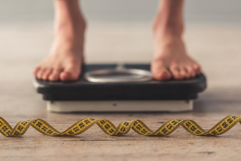 A person stands on a bathroom scale.