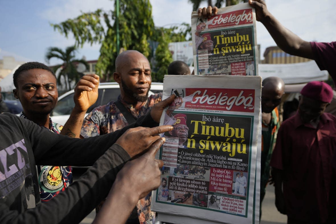 People chant as they hold newspapers with headlines of newly elected Nigeria’s President, Bola Tinubu of the All Progressives Congress, on the street in Lagos, Nigeria, Wednesday, March 1, 2023. (AP Photo/Sunday Alamba)