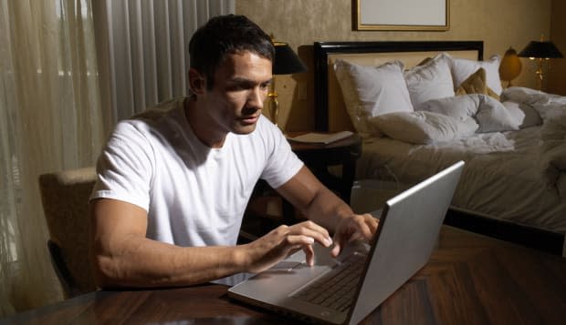 Man using laptop in bedroom