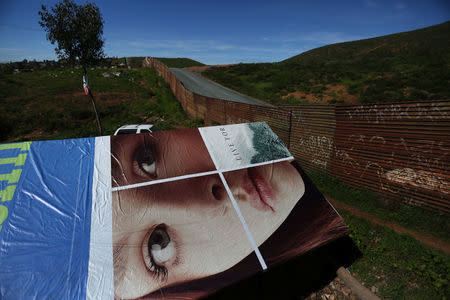 The roof of a house made with an advertisement banner is seen next to a section of the border fence separating Mexico and the United States, on the outskirts of Tijuana, Mexico. REUTERS/Edgard Garrido