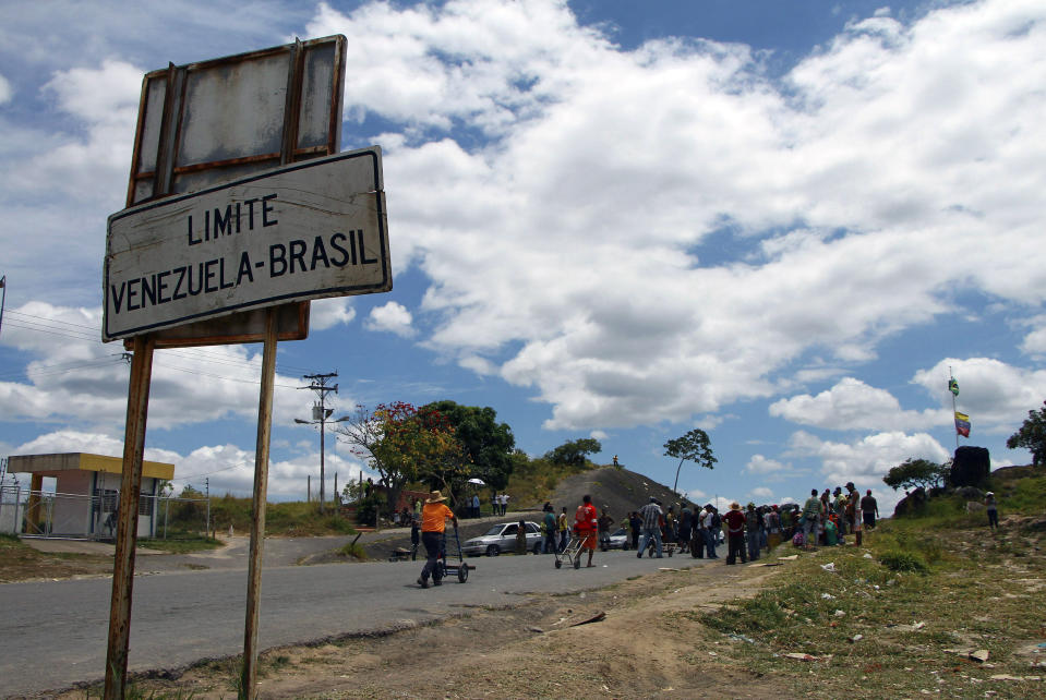 Venezuelans wait for the opening of the border in Pacaraima, Roraima state, Brazil, Friday, Feb. 22, 2019. Heightened tensions in Venezuela left a woman dead and a dozen injured near the border with Brazil on Friday, in the first deadly clash over the opposition's attempts to bring in emergency food and medicine that President Nicolas Maduro says isn't needed and has vowed to block. (AP Photo/Edmar Barros)