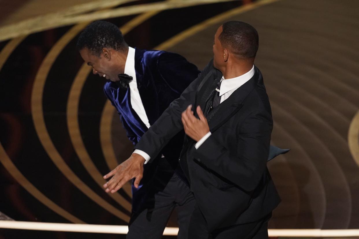 Will Smith, right, hits presenter Chris Rock on stage while presenting the award for best documentary feature at the Oscars on March 27, 2022, at the Dolby Theatre in Los Angeles.