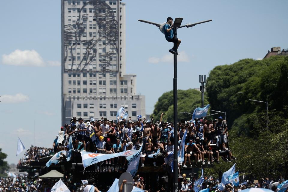 Fans of Argentina wait for the bus with Argentina's players to pass through the Obelisk to celebrate after winning the Qatar 2022 World Cup tournament in Buenos Aires on December 20, 2022. - Millions of ecstatic fans are expected to cheer on their heroes as Argentina's World Cup winners led by captain Lionel Messi began their open-top bus parade of the capital Buenos Aires on Tuesday following their sensational victory over France. (Photo by Emiliano Lasalvia / AFP) (Photo by EMILIANO LASALVIA/AFP via Getty Images)