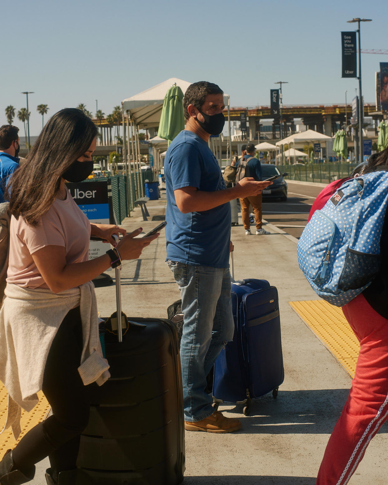 Viajeros en el Aeropuerto Internacional de Los Ángeles esperan por vehículos de viajes privados en la zona del aeropuerto destinada para recoger pasajeros en Los Ángeles, el 21 de mayo de 2021. (David Lopez Osuna/The New York Times)