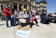 Annette Rafacz gives Manny Orovcoa a free haircut at the State Capitol during a rally in Lansing, Mich., Wednesday, May 20, 2020. Barbers and hair stylists are protesting the state's stay-at-home orders, a defiant demonstration that reflects how salons have become a symbol for small businesses that are eager to reopen two months after the COVID-19 pandemic began. (AP Photo/Paul Sancya)