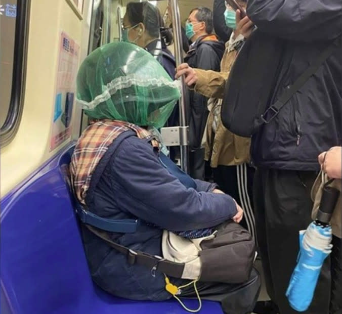 有民眾搭捷運時驚見一名婦人不但頭戴安全帽，還在帽外再罩上1層綠色紗網，如此防疫奇招讓全車乘客都看傻眼！ （圖片翻攝爆廢公社）