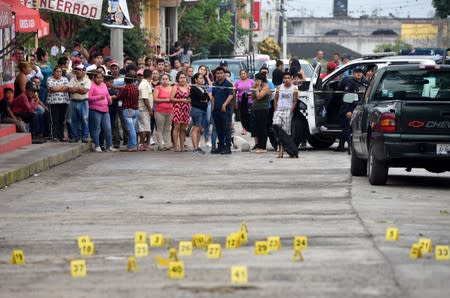FILE PHOTO: People stand near bullet casings on the ground at a crime scene after a shootout in the municipality Tuzamapan