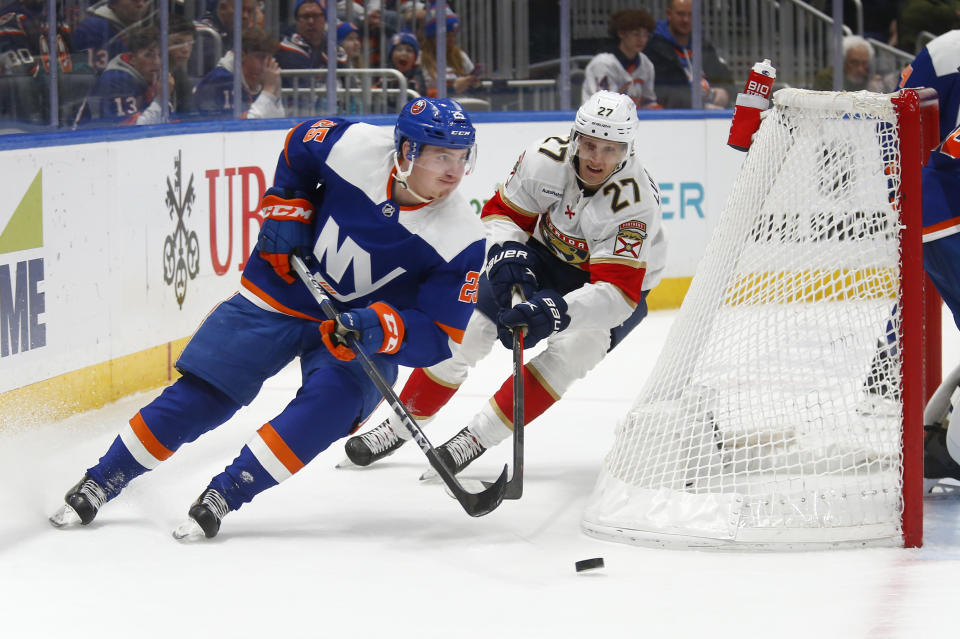 New York Islanders defenseman Sebastian Aho (25) carries the puck behind his net with Florida Panthers center Eetu Luostarinen (27) in pursuit during the first period of an NHL hockey game, Saturday, Jan. 27, 2024, in Elmont, N.Y. (AP Photo/John Munson)