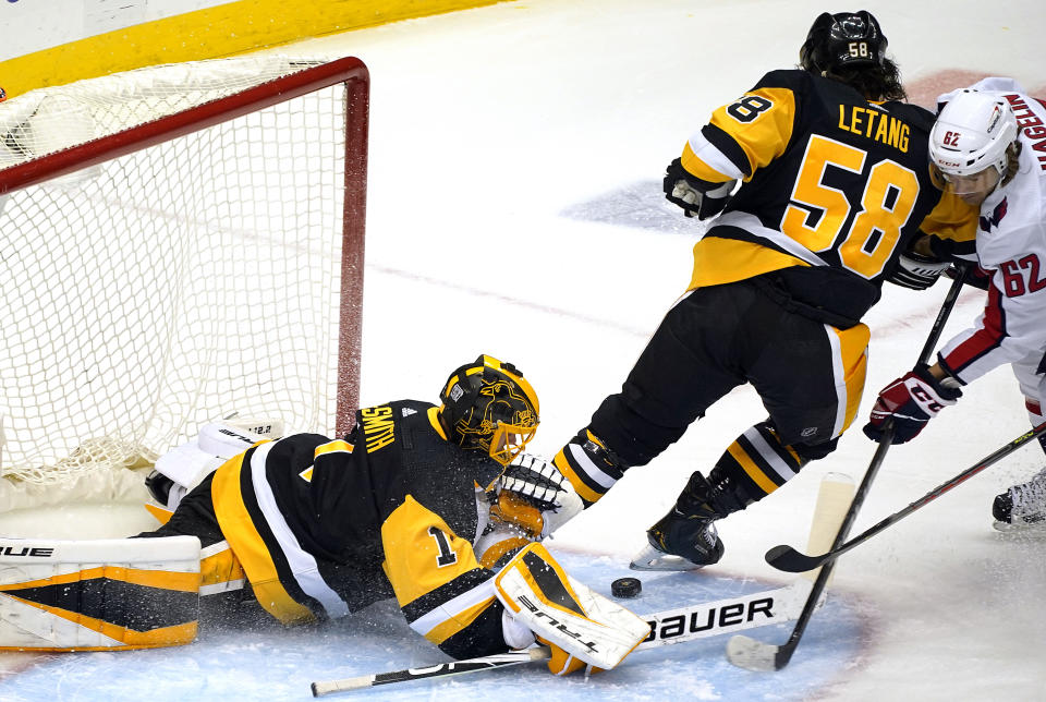 Washington Capitals' Carl Hagelin (62) can't get his stick on a rebound off Pittsburgh Penguins goaltender Casey DeSmith (1) with Penguins' Kris Letang (58) defending during the first period of an NHL hockey game in Pittsburgh, Tuesday, Jan. 19, 2021. (AP Photo/Gene J. Puskar)