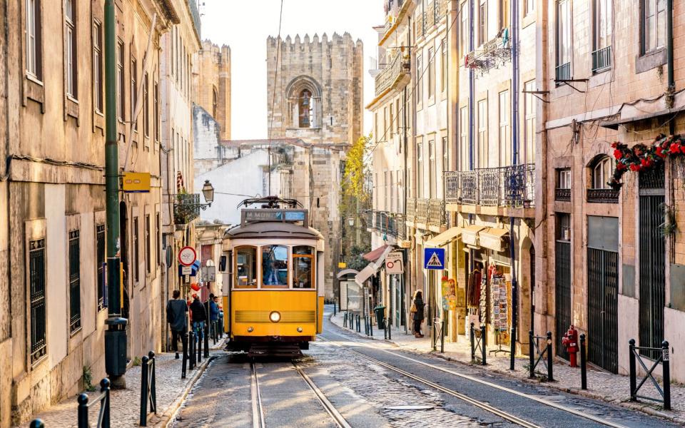 Street in Lisbon old town with yellow tram and Lisbon Cathedral in background - Moment RF 