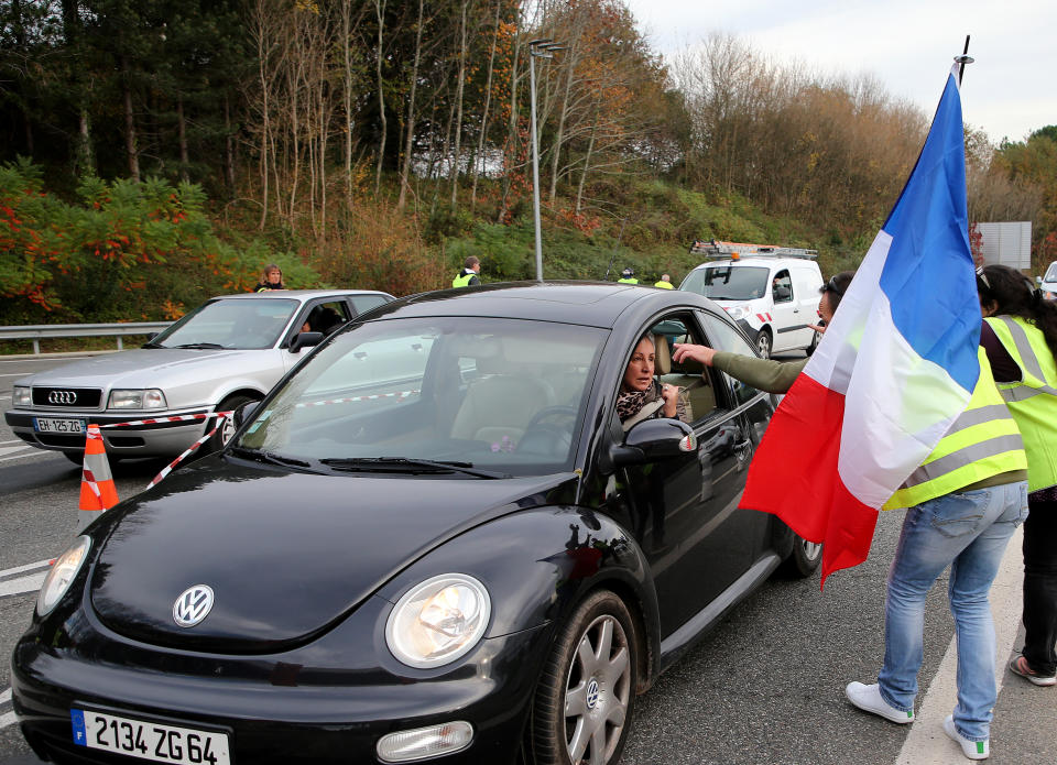 A demonstrator holds a french flag at the toll gates on a motorway at Biarritz southwestern France, Wednesday, Dec. 5, 2018. The concessions made by French president Emmanuel Macron's government in a bid to stop the huge and violent anti-government demonstrations seemed on Wednesday to have failed to convince protesters, with trade unions and disgruntled farmers now threatening to join the fray.(AP Photo/Bob Edme)