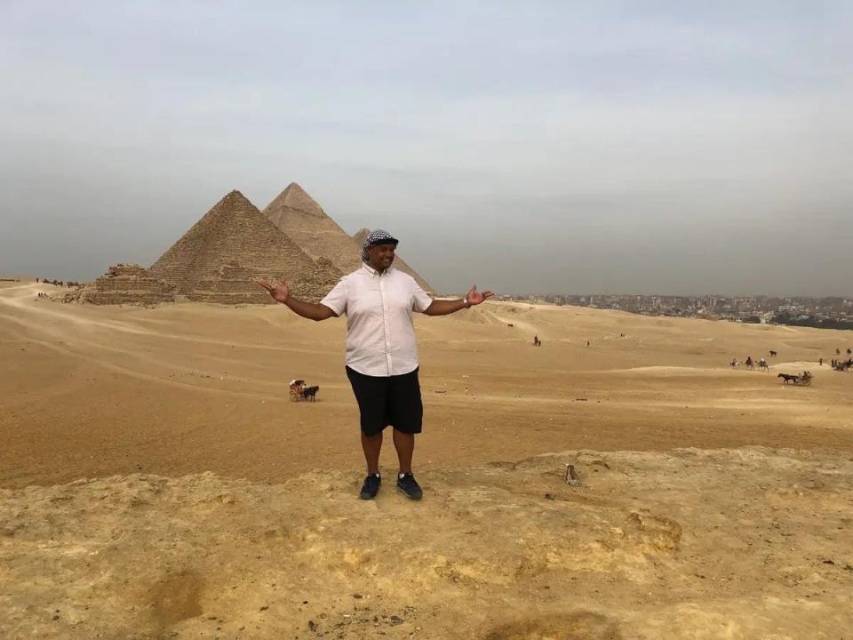 A man posing in front of the pyramids in Egypt.