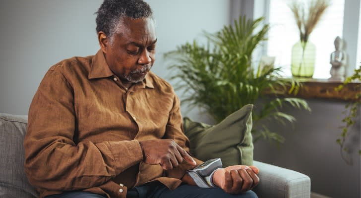 A senior checking his blood pressure with a machine that was covered through Medicare.