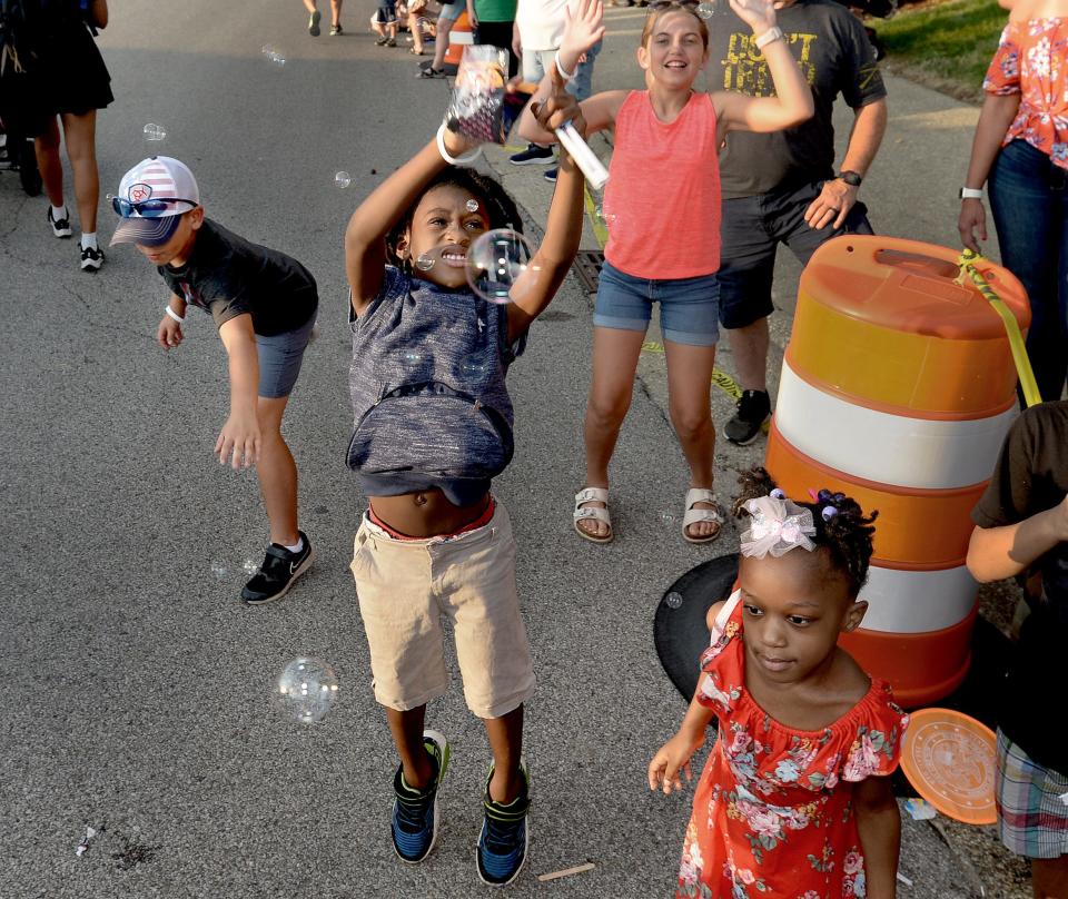 Keonta-Eden Booker, 7, of Springfield, center, tries to catch bubbles, along with other children, coming from the Bank of Springfield float during the Illinois State Fair Twilight Parade Thursday, August 10, 2023.