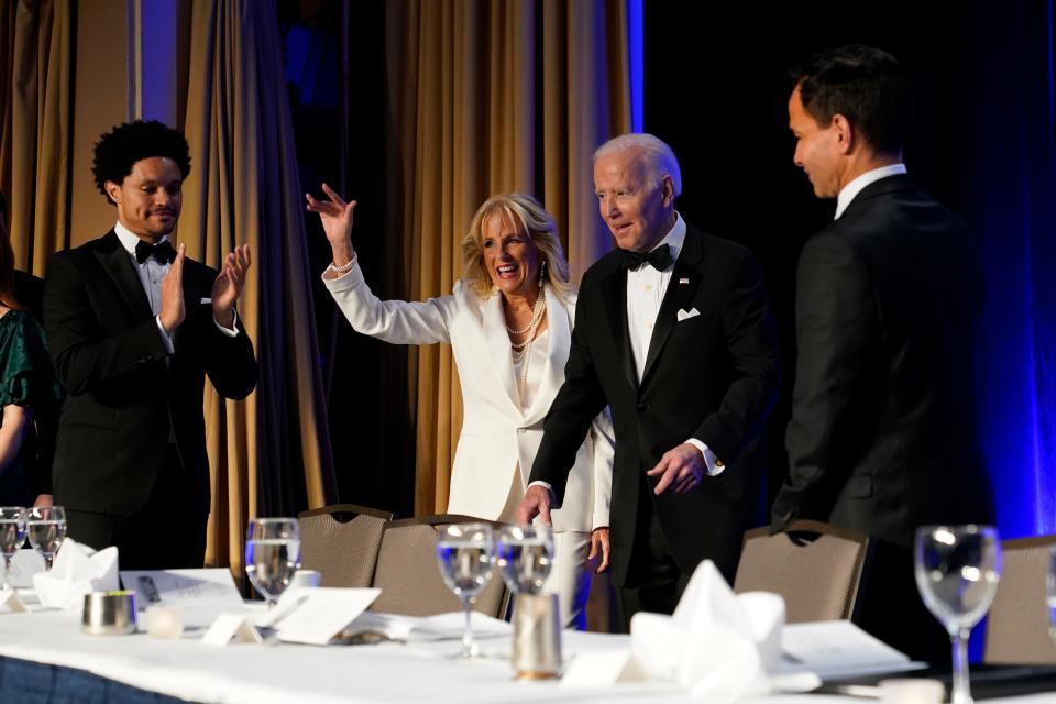 As comedian Trevor Noah applauds, President Joe Biden and first lady Jill Biden arrive at the annual White House Correspondents' Association dinner on April 30, 2022.
