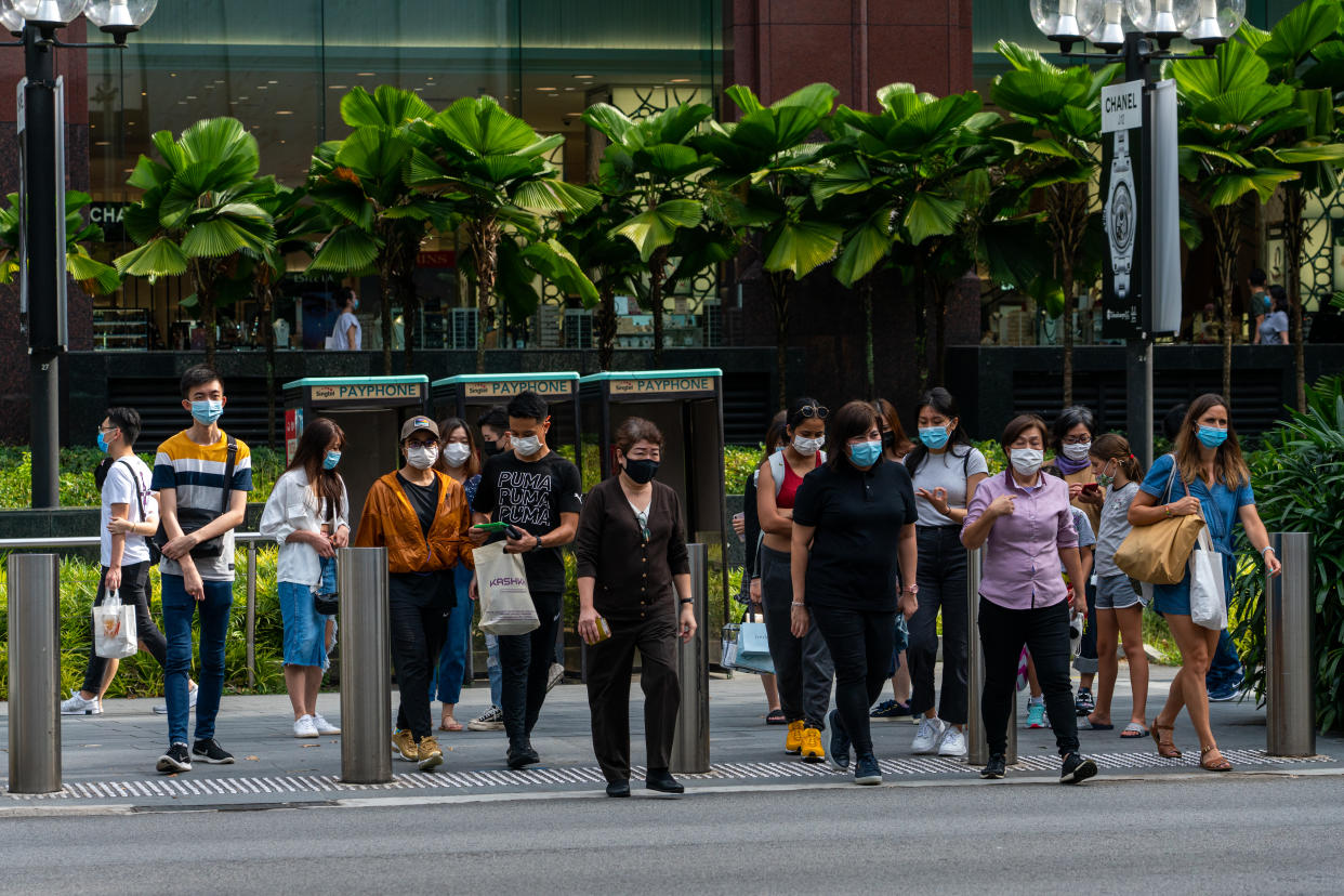 Group of people at Orchard Road wearing face masks in Singapore crossing the street.