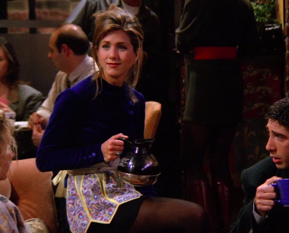 Rachel wearing a blue velvet shirt and a pretty apron over a black skirt