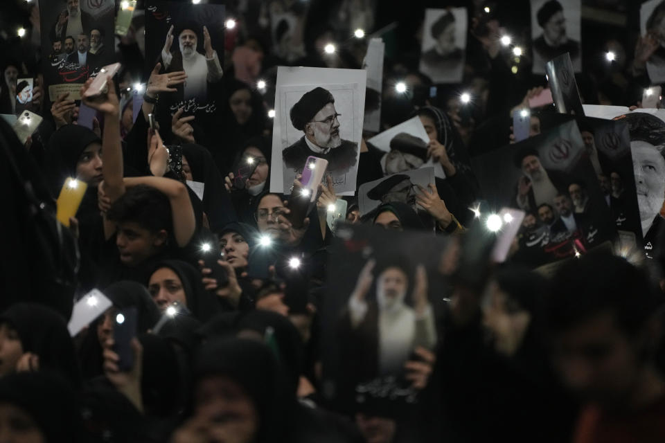 Mourners hold up a posters of the late Iranian President Ebrahim Raisi at the mam Khomeini Grand Mosque in Tehran, Iran, Tuesday, May 21, 2024 during a funeral ceremony for him and his companions who were killed in a helicopter crash on Sunday in a mountainous region of the country's northwest. Mourners in black began gathering Tuesday for days of funerals and processions for Iran's late president, foreign minister and others killed in a helicopter crash, a government-led series of ceremonies aimed at both honoring the dead and projecting strength in an unsettled Middle East. (AP Photo/Vahid Salemi)