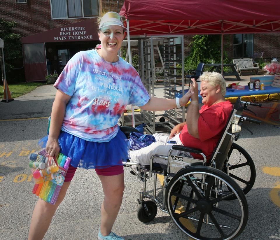 Riverside Rest Home activities director Kristina LaPointe gives a high five to Tammy, a resident, during Carnival Day July 19, 2023.