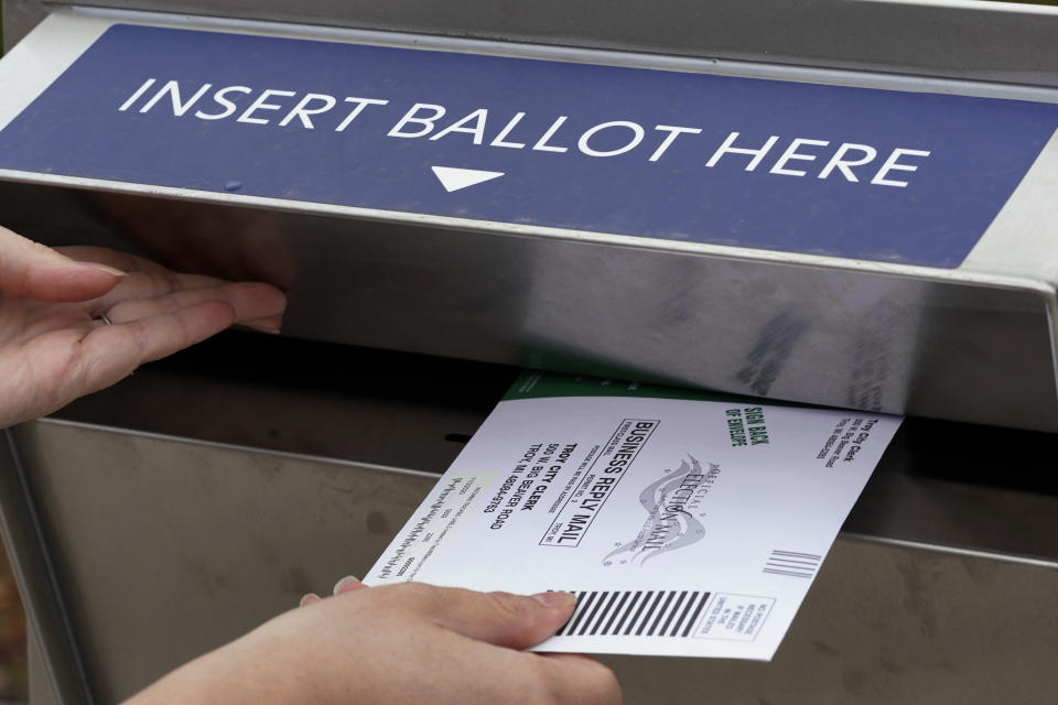 FILE - In this Thursday, Oct. 15, 2020, file photo, Nikki Schueller inserts her absentee voter ballot into a drop box in Troy, Mich. Just days before the presidential election, millions of mail-in ballots have still not been returned in key battleground states. Many of those are due in county offices by Tuesday, Nov. 3, but the latest Postal Service delivery data suggests it’s too late for voters to drop their ballots in the mail. (AP Photo/Paul Sancya, File)