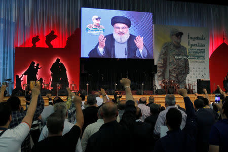 Hezbollah leader Sayyed Hassan Nasrallah addresses his supporters from a screen, during a ceremony marking a year after Hezbollah commander Mustafa Badreddine(picture on banner) was killed in an attack in Syria, in Beirut's southern suburbs, Lebanon May 11, 2017. REUTERS/Aziz Taher