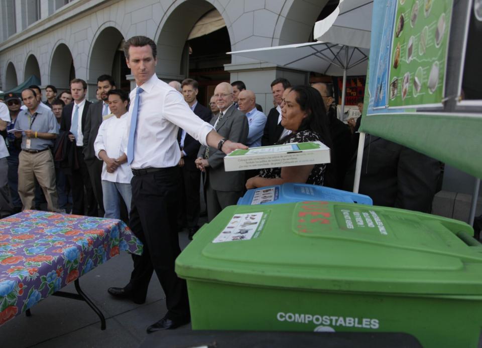 Then-San Francisco Mayor Gavin Newsom places a compostable pizza box on a bin.