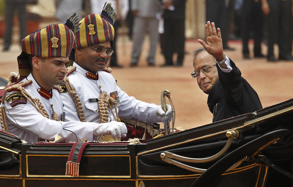 FILE- In this July 25, 2012 file photo, Pranab Mukherjee, right, in a traditional horse driven carriage, waves to the media as he arrives to be sworn in as India's 13th president at the Presidential Palace, in New Delhi, India. Former President Pranab Mukherjee, who was a key troubleshooter in managing fractious coalitions as a member of India's long-governing Congress party died Monday evening. He was 84. Mukherjee had emergency surgery for a blood clot in his brain on August 10 at New Delhi's Army Hospital Research and Referral. (AP Photo/Manish Swarup, File)