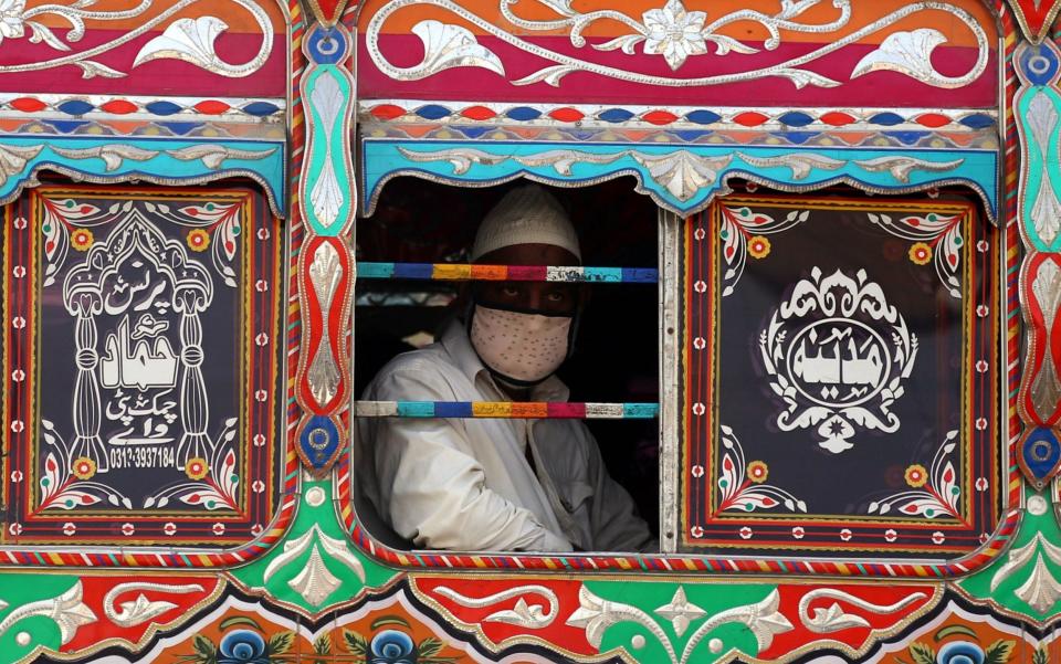 A man wears protective mask in a public transport, during partial lockdown in Karachi, Pakistan - Shutterstock