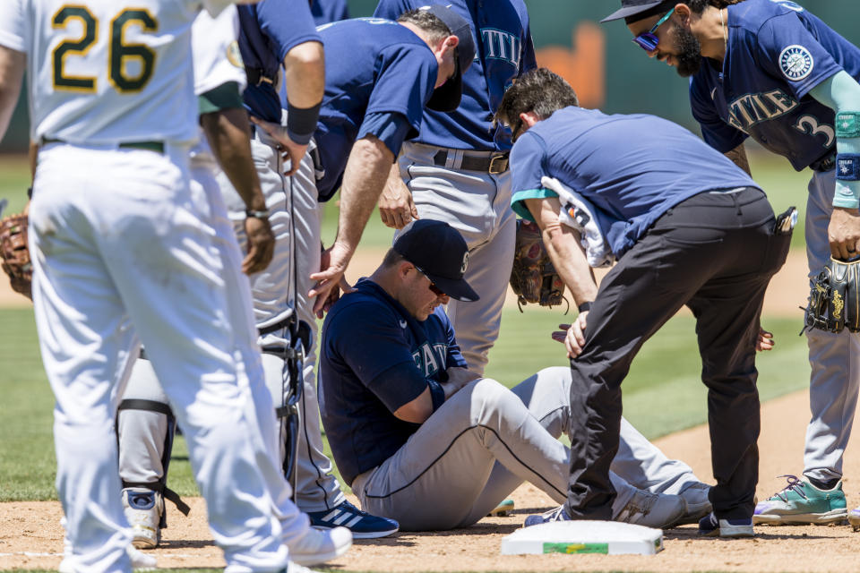 Seattle Mariners first baseman Ty France, on ground, is attended to after he sustained an injury as Oakland Athletics' Sheldon Neuse. not seen, reached first base on a single during the fifth inning of a baseball game in Oakland, Calif., Thursday, June 23, 2022. (AP Photo/John Hefti)