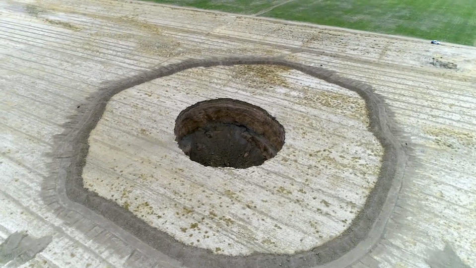 This frame grab from an Aug. 8, 2018 video provided by Iranian Students' News Agency, ISNA, shows an aerial view of a massive hole caused by drought and excessive water pumping in Kabudarahang, in Hamadan province, in western Iran. Some sinkholes formed in western Iran are as deep as 60 meters (196 feet). (ISNA via AP)