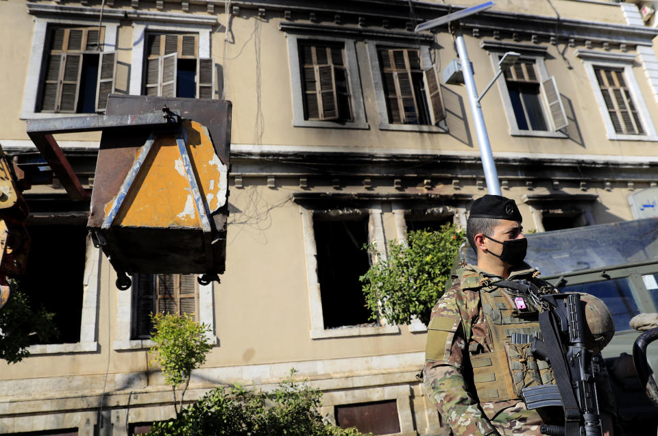 A Lebanese army soldier stand guards outside the building of Tripoli municipality that was set on fire by protesters Thursday night, during a protest against deteriorating living conditions and strict coronavirus lockdown measures, in Tripoli, Lebanon, Friday, Jan. 29, 2021. (AP Photo/Hussein Malla)