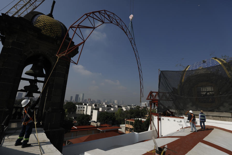 A worker guides a steel arch being lifted by a crane into place overtop the damaged cupola, as part of a frame that will support a temporary metal roof, in the early stages of reconstruction work at Nuestra Senora de Los Angeles (Our Lady of Angels) church, three years after an earthquake collapsed nearly half of its 18th-century dome, in Mexico City, Wednesday, Sept. 23, 2020. The dome didn’t collapse at the moment of the quake, but rather five days later, leaving time to get people and precious objects out. (AP Photo/Rebecca Blackwell)