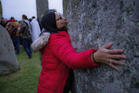 A woman kisses one of the standing stones during Summer Solstice at Stonehenge, where some people jumped over the fence to enter the stone-circle to watch the sun rise at dawn of the longest day of the year in the UK, in Amesbury, England, Monday June 21, 2021. The prehistoric monument of ancient stones have been officially closed for the celebrations due to the coronavirus lockdown, but groups of people ignored the lockdown to mark the Solstice, watched by low key security. (Ben Birchall/PA via AP)