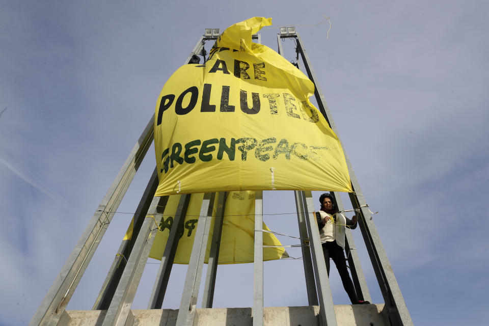 A Greenpeace activist displays a banner reading 'Our politics are pulled' outside the COP25 climate talks congress in Madrid, Spain, Friday, Dec. 13, 2019. The United Nations Secretary-General has warned that failure to tackle global warming could result in economic disaster. (AP Photo/Paul White)