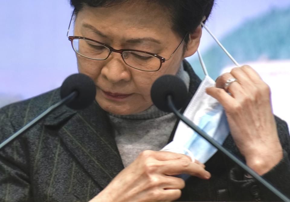 Hong Kong Chief Executive Carrie Lam takes off her face mask before a news conference on Secretary of Home Affairs Caspar Tsui's resignation in Hong Kong, Monday, Jan. 31, 2022. Tsui resigned Monday for attending a birthday party with about 200 guests in early January as the city was battling a coronavirus surge. At least one guests later tested positive, and Tsui was among several officials and lawmakers ordered to quarantine after the party, which was held for Witman Hung, a delegate to China's legislature. (AP Photo/Vincent Yu)