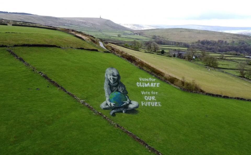 Bradford Telegraph and Argus: Bradford-born artist Jamie Wardley has created a 165ft (50m) high anamorphic painting of a girl holding the Earth in a Hebden Bridge field to mark Earth Day.