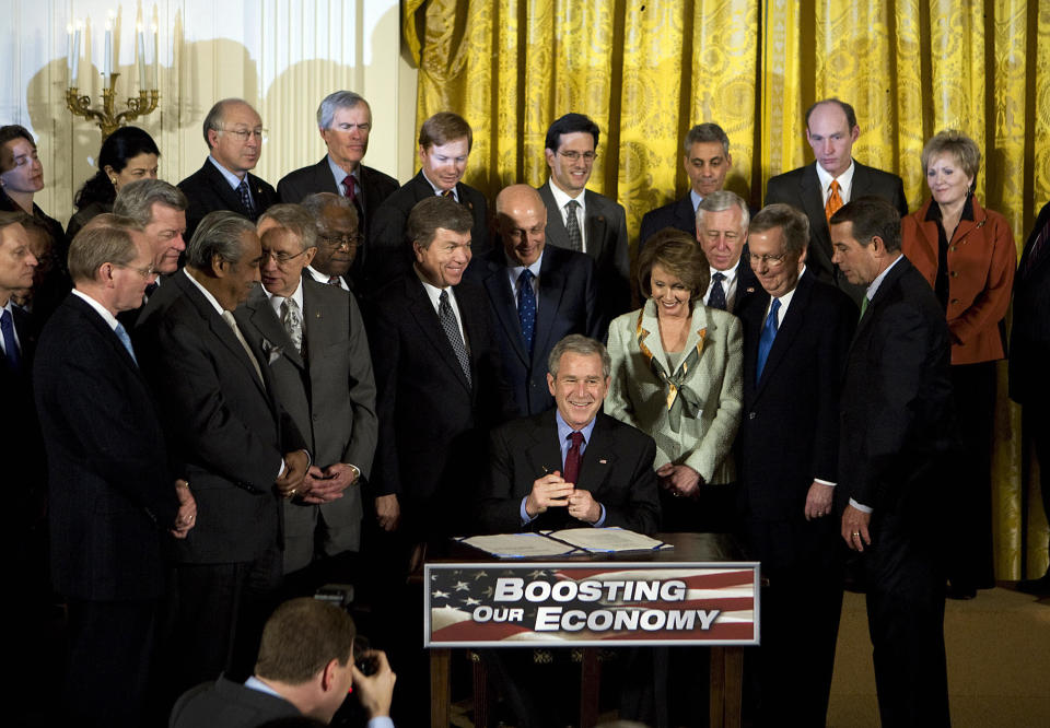 US President George W. Bush (seated) flanked by Congress members and members of his cabinet signs the Economic Stimulus Act of 2008, on February 13, 2008 in the East Room of the White House in Washington, DC. Bush signed the two-year, 168-billion-USD stimulus package, praising it as "a booster shot" for the battered US economy. "We have come together on a single mission, and that is to put the people's interest first," Bush said.  AFP PHOTO/Mandel NGAN (Photo credit should read MANDEL NGAN/AFP via Getty Images)