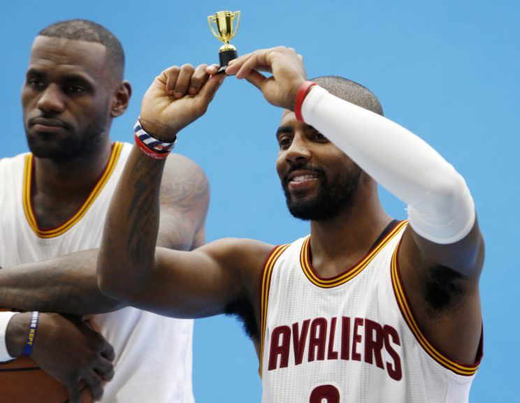 Kyrie Irving raises a tiny trophy as LeBron James looks uncomfortable. (AP)